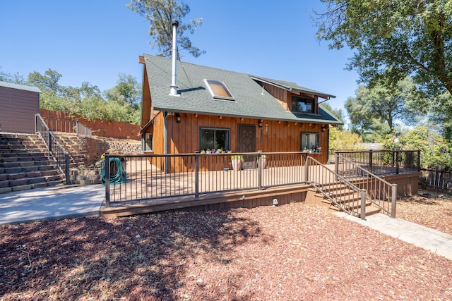 chalet / cabin with a shingled roof, fence, stairway, and a wooden deck