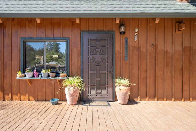 entrance to property with a shingled roof and board and batten siding