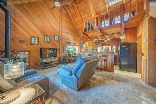 living room featuring light colored carpet, wood walls, wood ceiling, beamed ceiling, and a wood stove