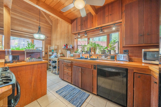 kitchen featuring butcher block countertops, dishwasher, wood walls, and a sink