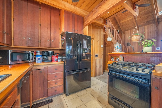 kitchen featuring light tile patterned floors, wooden ceiling, wooden walls, wood counters, and black appliances