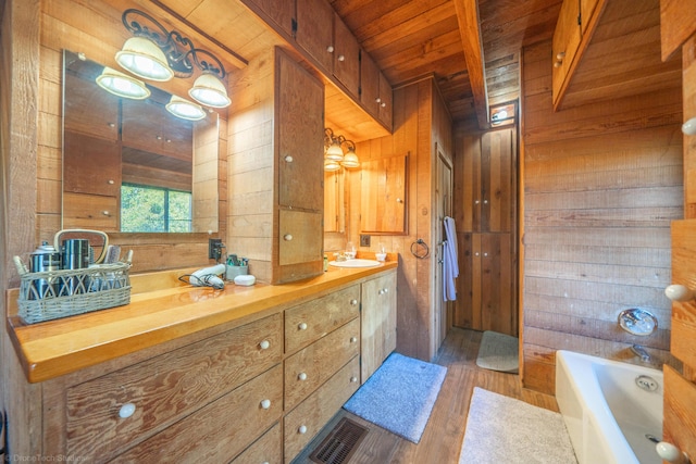 bathroom with wood walls, visible vents, a bathtub, and vanity