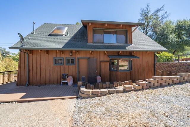 rustic home with a shingled roof and a deck