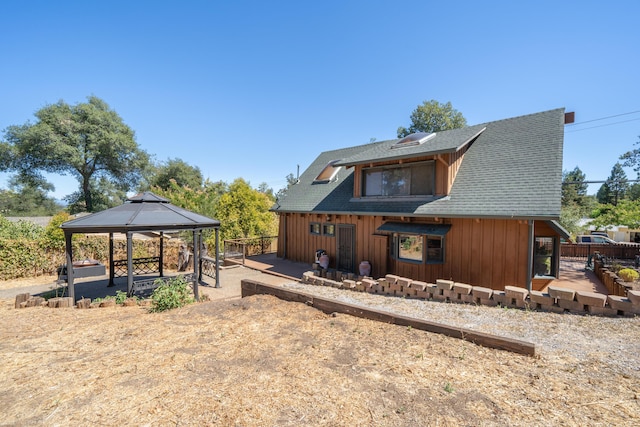 rear view of house with a shingled roof, a patio, fence, a gazebo, and board and batten siding