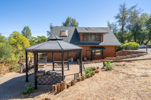 view of front of home with a gazebo, board and batten siding, a patio area, and roof with shingles