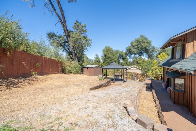 view of yard featuring a fenced backyard, a storage unit, an outdoor structure, and a gazebo