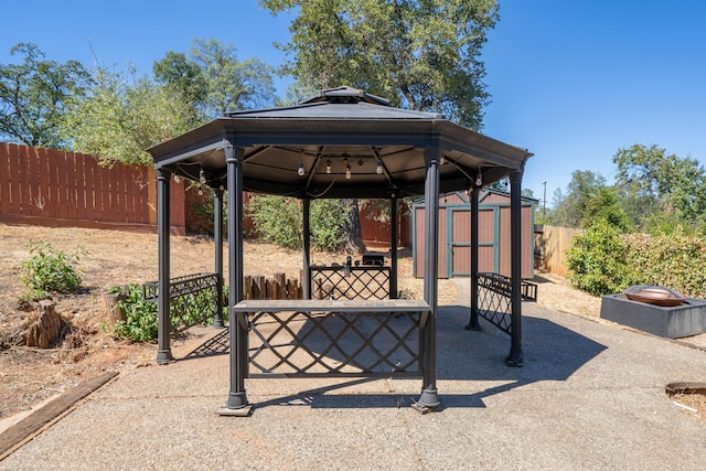 view of patio featuring an outbuilding, a gazebo, a storage unit, and fence