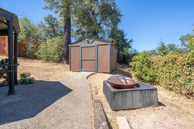 view of shed with an outdoor fire pit and a fenced backyard