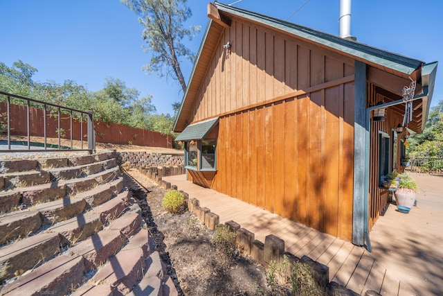 view of side of home featuring board and batten siding and fence