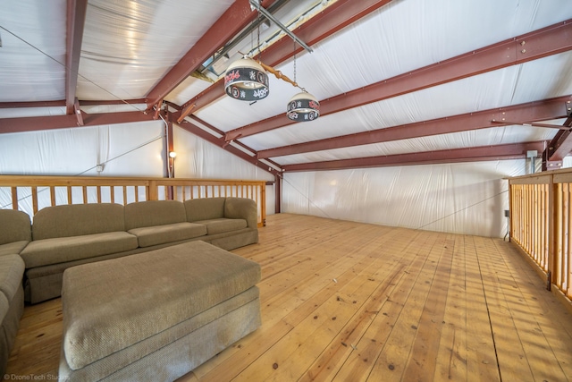 living area with vaulted ceiling with beams, wood-type flooring, and a garage