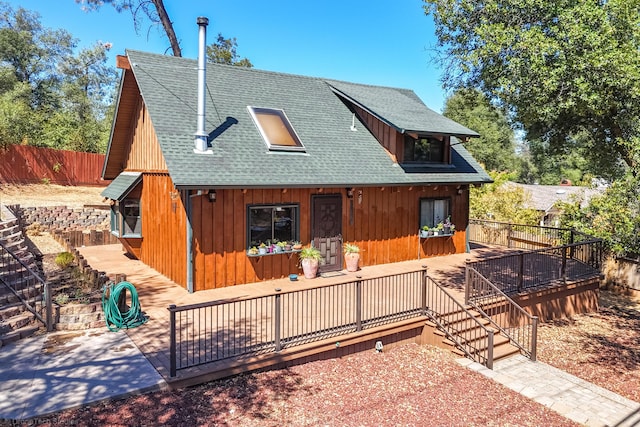 rustic home featuring roof with shingles, fence, a wooden deck, and stairs