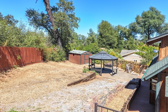 view of yard featuring an outbuilding, a patio, a gazebo, fence, and a shed