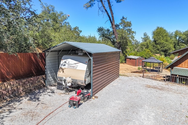 exterior space featuring a carport, driveway, an outdoor structure, and fence