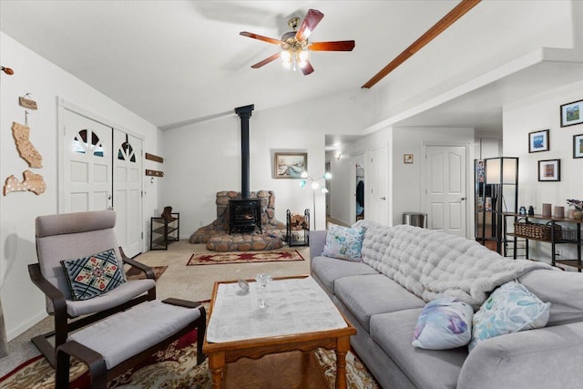 carpeted living area featuring vaulted ceiling, a wood stove, and a ceiling fan