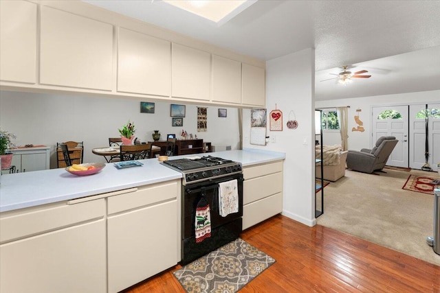 kitchen with black gas stove, light countertops, and wood finished floors