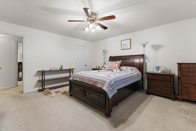bedroom featuring baseboards, a textured ceiling, ceiling fan, and light carpet
