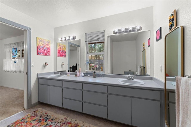 full bath featuring double vanity, a textured ceiling, and a sink