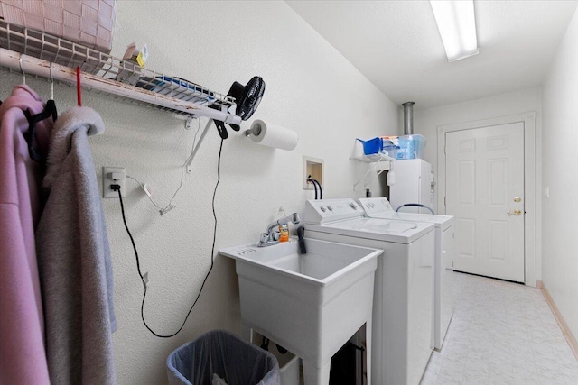clothes washing area with washing machine and clothes dryer, baseboards, laundry area, light floors, and a sink