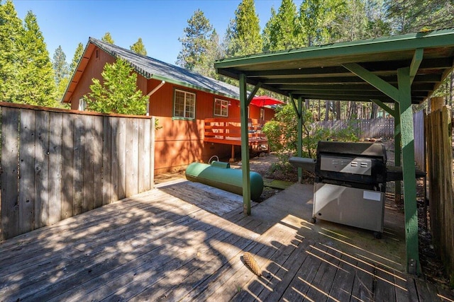 wooden terrace featuring fence and a grill