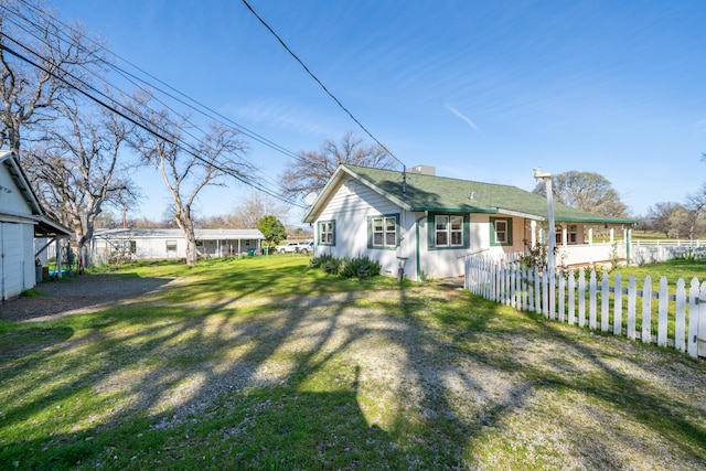 exterior space featuring a chimney, a shingled roof, a yard, and fence