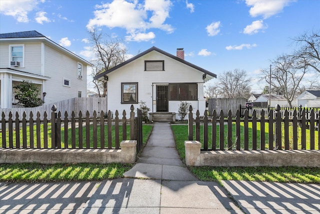 bungalow with a fenced front yard, a chimney, and a front lawn