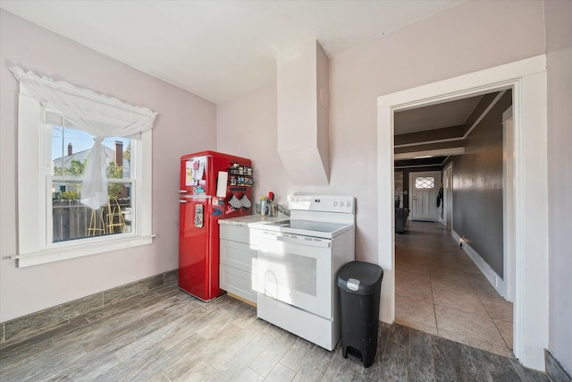 kitchen with light wood-style flooring, baseboards, electric stove, light countertops, and freestanding refrigerator