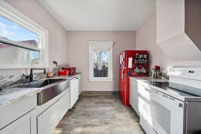 kitchen with white appliances, a sink, white cabinetry, and exhaust hood