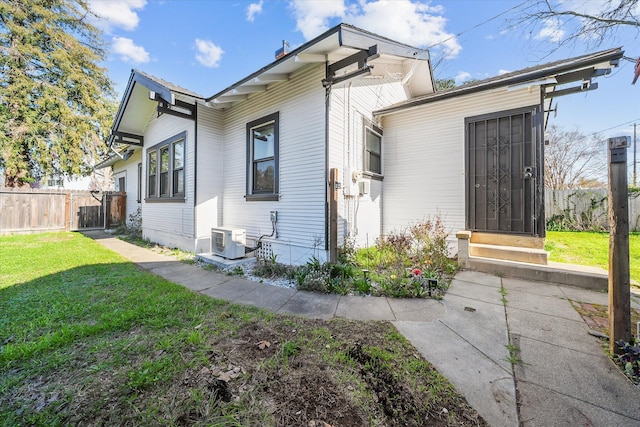 exterior space with ac unit, fence, and a front yard