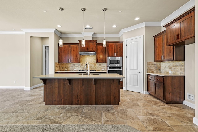 kitchen featuring a kitchen island with sink, ornamental molding, light countertops, under cabinet range hood, and appliances with stainless steel finishes