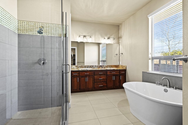 bathroom with double vanity, a freestanding tub, a shower stall, and tile patterned flooring