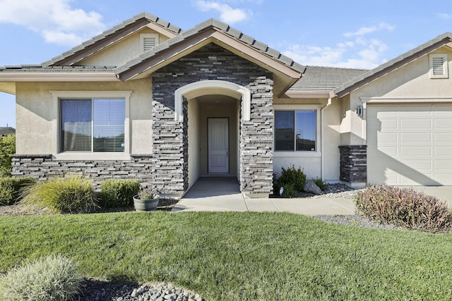 view of exterior entry featuring a lawn, stone siding, and stucco siding