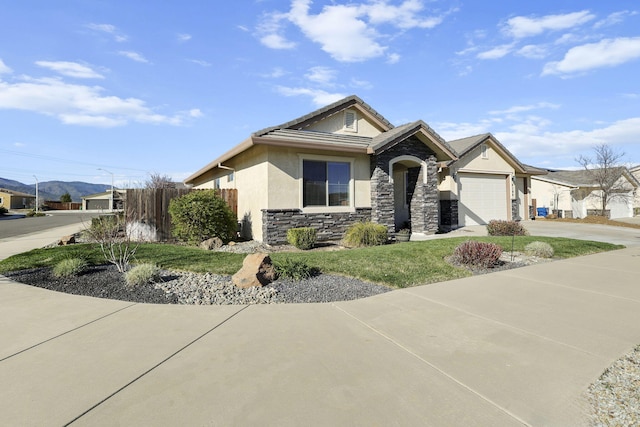 view of front of house featuring an attached garage, fence, stucco siding, stone siding, and driveway