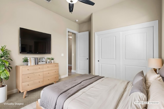 bedroom with a closet, baseboards, light colored carpet, and a ceiling fan