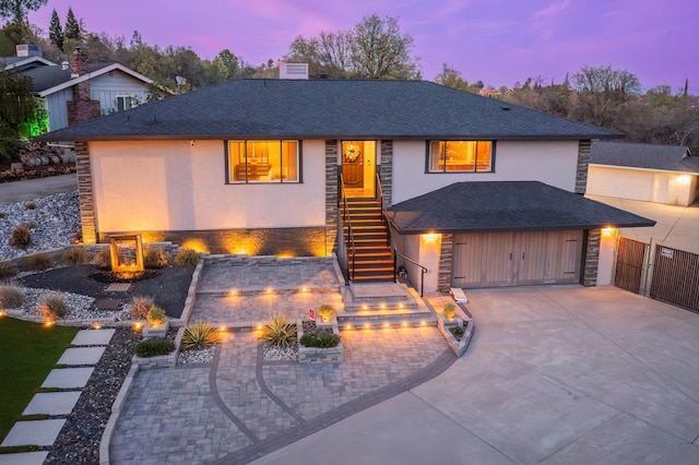 view of front of home with stairway, stone siding, driveway, and stucco siding