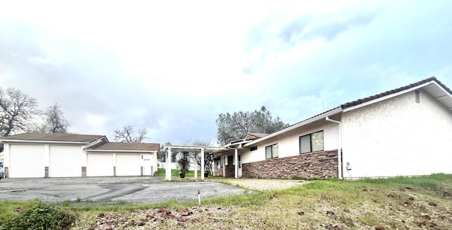 view of front of home featuring stone siding, driveway, and stucco siding