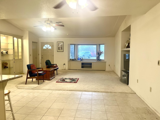 living area featuring visible vents, built in shelves, a ceiling fan, light tile patterned floors, and light colored carpet