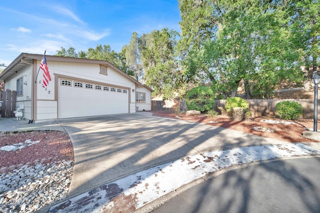 view of front facade featuring an attached garage, driveway, and fence