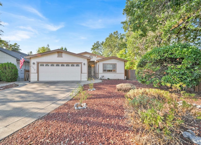 single story home with concrete driveway, an attached garage, and fence