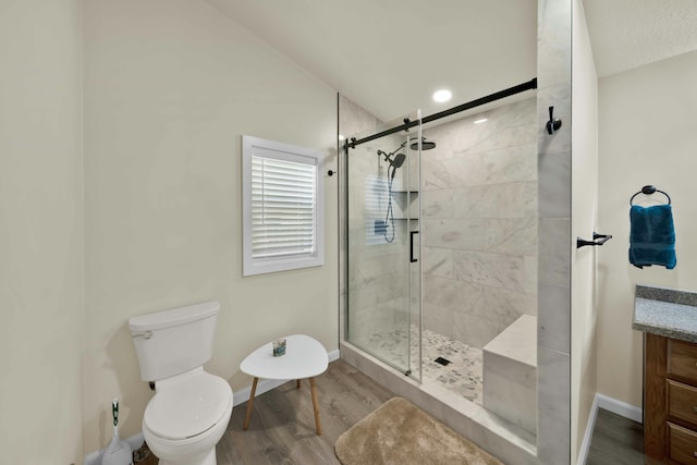 full bath with a shower stall, baseboards, toilet, wood finished floors, and vanity