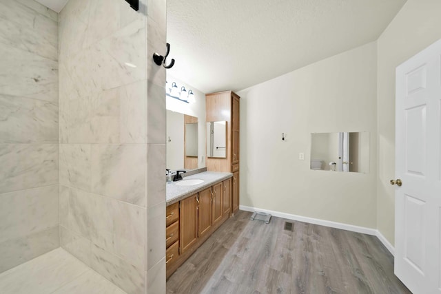 full bath featuring baseboards, a textured ceiling, wood finished floors, and vanity