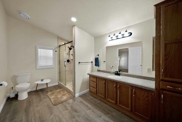 full bath featuring toilet, a stall shower, wood finished floors, baseboards, and vanity