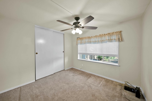 unfurnished bedroom with baseboards, a closet, carpet floors, and ceiling fan