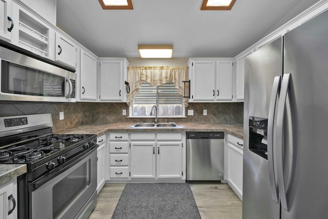 kitchen with a sink, decorative backsplash, white cabinets, and stainless steel appliances