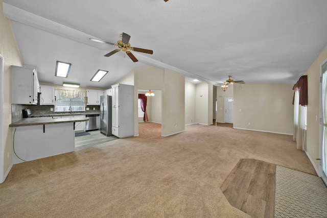 living area with baseboards, light carpet, ceiling fan, and vaulted ceiling