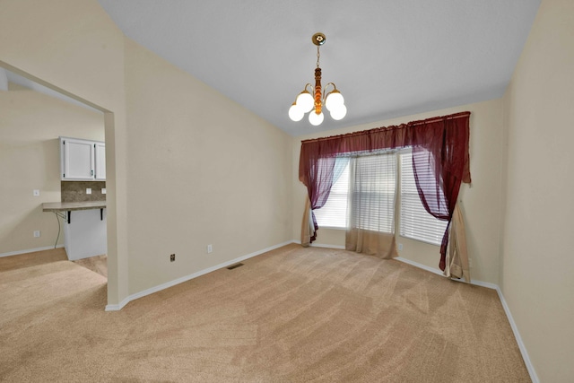 empty room featuring visible vents, a notable chandelier, baseboards, light colored carpet, and vaulted ceiling