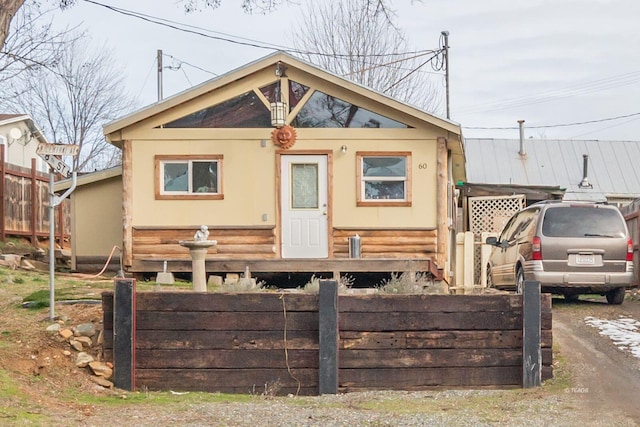 bungalow featuring fence and stucco siding