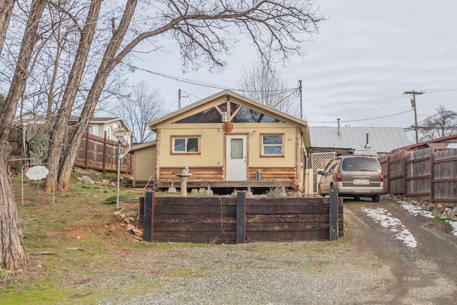 view of front of property with dirt driveway and fence