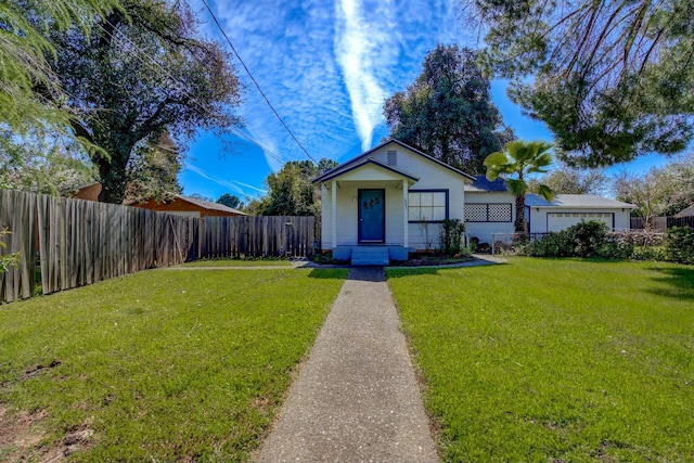 bungalow featuring an attached garage, a front yard, and fence