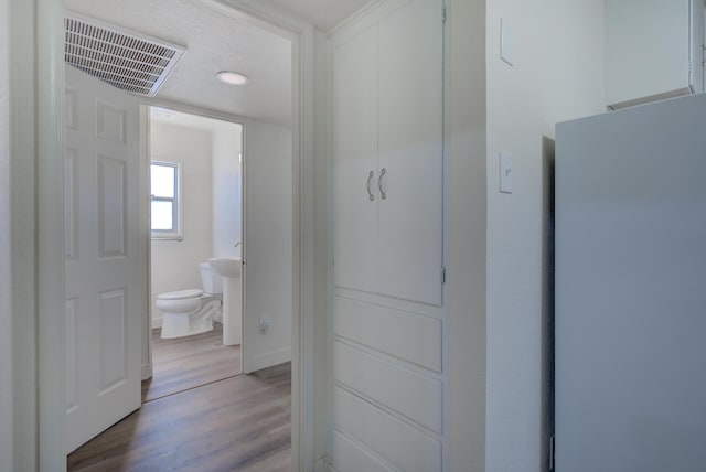 interior space featuring visible vents, light wood-style flooring, and a textured ceiling