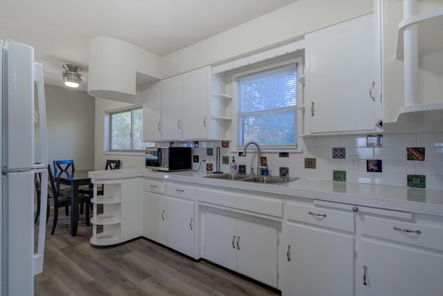 kitchen featuring open shelves, stainless steel microwave, freestanding refrigerator, and a sink